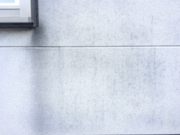 窓の下に黒い雨だれ汚れが付いた外壁
